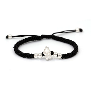 Macro view of a black braided cord bracelet with a silver cartoon character charm