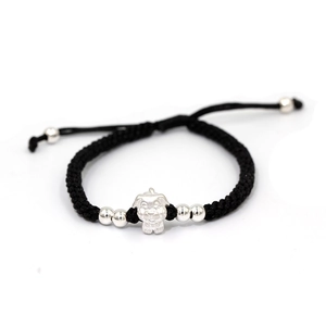 Macro shot of handcrafted black woven bracelet with silver puppy pendant and beads