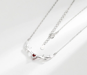 Macro shot of S925 sterling silver deer horn necklace with a red heart-shaped gemstone