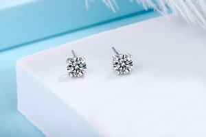Macro detail of classic four-prong set cubic zirconia silver stud earrings on white pedestal