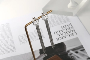 Detail of silver star tassel earrings hanging on a vintage jewelry stand over a magazine