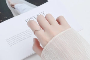 Close-up of a 925 silver wavy minimalist ring worn on a finger with an elegant white sleeve