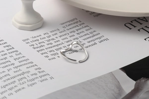 Detail of minimalist wavy silver ring with an abstract heart shape on a ceramic base