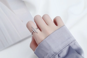 Close-up of a hollow geometric cross ring in silver finish on a model's finger
