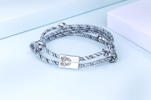 Primer plano de pulseras magnéticas para parejas en plata S925 con cordón trenzado y grabado