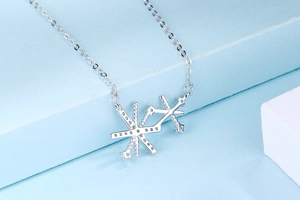 Détail du pendentif argenté géométrique en étoile avec chaîne fine sur fond bleu clair