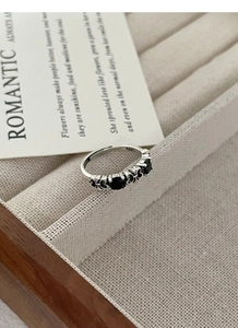 Detail of vintage S925 silver ring with black gemstones and heart patterns in a jewelry box