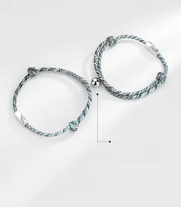 Close-up of magnetic matching bracelets for couples with woven ropes and silver charms