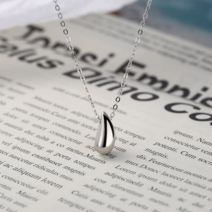 Vue macro d'un pendentif goutte en argent poli sur une chaîne fine avec finition brillante