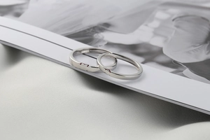 Macro shot of S925 silver couple rings forming a red enamel heart on a white magazine