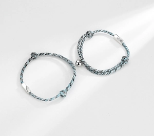 Detail of woven magnetic couple bracelets with engraved feather metal plate and cord