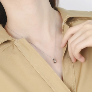 Gros plan d'un collier avec pendentif goutte en argent S925 sur un mannequin féminin