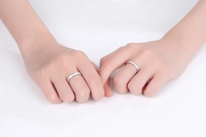 Close-up of S925 silver couples rings with small red heart details worn on fingers