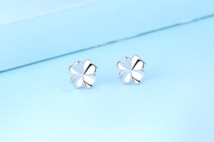 Polished S925 sterling silver four-leaf clover stud earrings on a light blue background