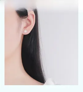 Gros plan de boucles d'oreilles flocons de neige en argent S925 portées par un modèle