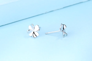 Detailed close-up of S925 sterling silver four-leaf clover stud earrings on blue background