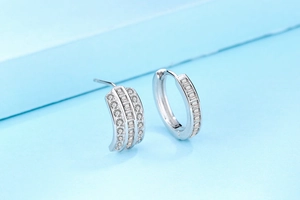 Macro shot of S925 silver earrings with triple row zircon stones on blue background