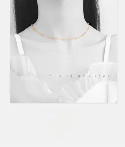 Close-up of minimalist gold choker necklace with small beads on a model with white lace