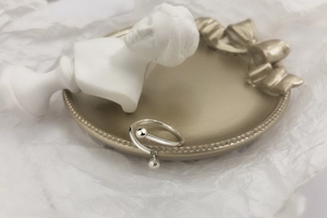 Detailed macro shot of S925 sterling silver cross ring with ball charm on a decorative tray