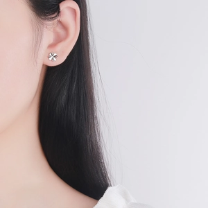 Minimalist S925 sterling silver four-leaf flower stud earrings worn by a model