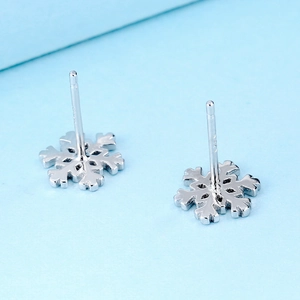 Boucles d'oreilles flocons en argent sterling S925 sur fond bleu clair minimaliste