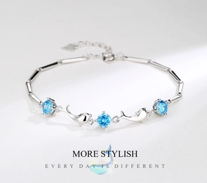 Detail of S925 silver dolphin bracelet with blue zircons and engraved heart charm
