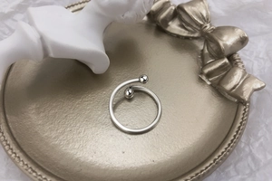 Macro shot of silver cross-over open ring with round beads on a gold decorative plate