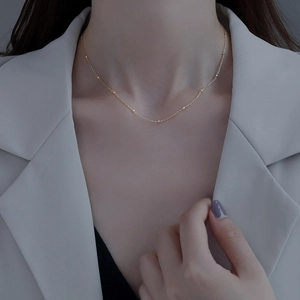 Elegant minimalist gold sterling silver choker with small beads worn with a grey blazer