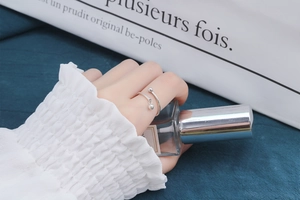 Detail of S925 sterling silver cross bead ring with a delicate hanging charm on finger