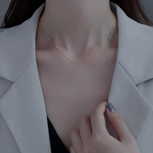 Minimalist gold satellite chain choker with small beads worn by model in white blazer