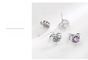 Dettaglio macro degli orecchini a cuore in argento S999 con zirconi chiari e viola