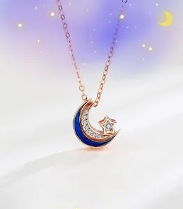 Gros plan du collier étoile et lune en or rose avec émail bleu et cristaux pavés