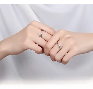 Gros plan de bagues de couple en argent S925 avec torsion mobius sur satin blanc