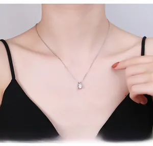 Close-up of a silver four-prong moissanite pendant necklace worn by a female model