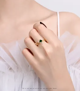 Detail of square green emerald ring on model finger with small white side diamonds