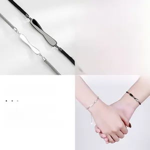 Detail of Mobius loop couple bracelets with silver and black charms on woven rope cords