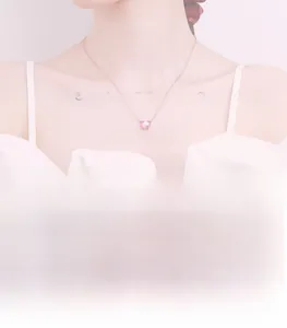 Detailed view of pink heart pendant necklace in rose gold worn by a female model
