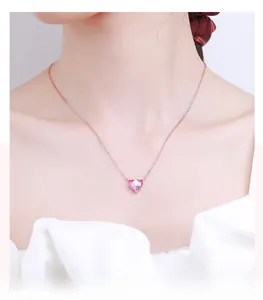 Detail of a pink heart-shaped gemstone necklace on a rose gold chain worn by a model