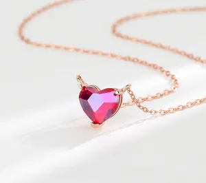 Macro view of rose gold devil heart necklace with a red zircon pendant and tail detail