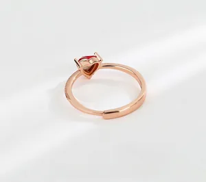 Detailed side view of rose gold heart ring with red gemstone in a four-prong setting