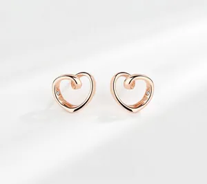 Dettaglio di orecchini a cuore in oro rosa con incisione LOVE e piccoli diamanti incastonati
