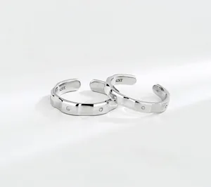 Macro shot of S925 sterling silver couple rings showing wavy texture and zircon stones