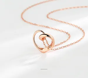 Dettaglio macro della collana con pendente a cuore cavo in oro rosa e piccola gemma