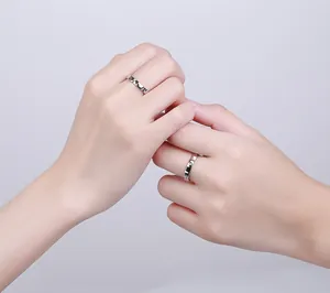 Close-up of couples S925 silver rings with black and white enamel on touching fingers
