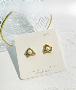 Dettaglio dei perni orecchini a triangolo in argento S925 con perle su carta bianca