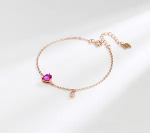 Detailed macro view of rose gold bracelet with heart red ruby and sparkling zircon pendant