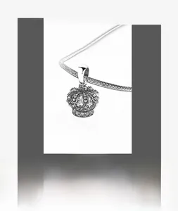 Détail macro d'un pendentif couronne en argent S925 vintage avec croix et diamants