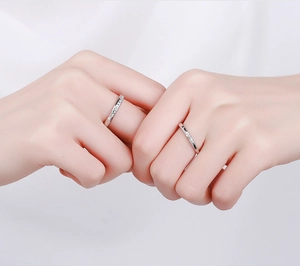 Detail of silver couple rings with geometric facets and micro-inlaid diamonds on fingers