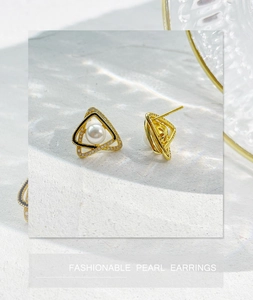 Dettaglio di orecchini di perle a triangolo geometrico in oro e nero con tocchi lucidi