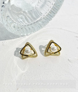 Dettaglio di orecchini a triangolo con perle, placcatura in oro e cristalli lucenti